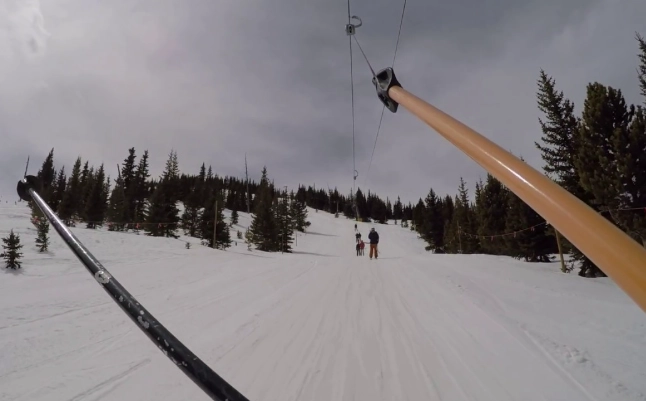 riding T-bar lift on snowboard